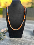 Zalmkleurige kralenketting met goudkleurige accenten